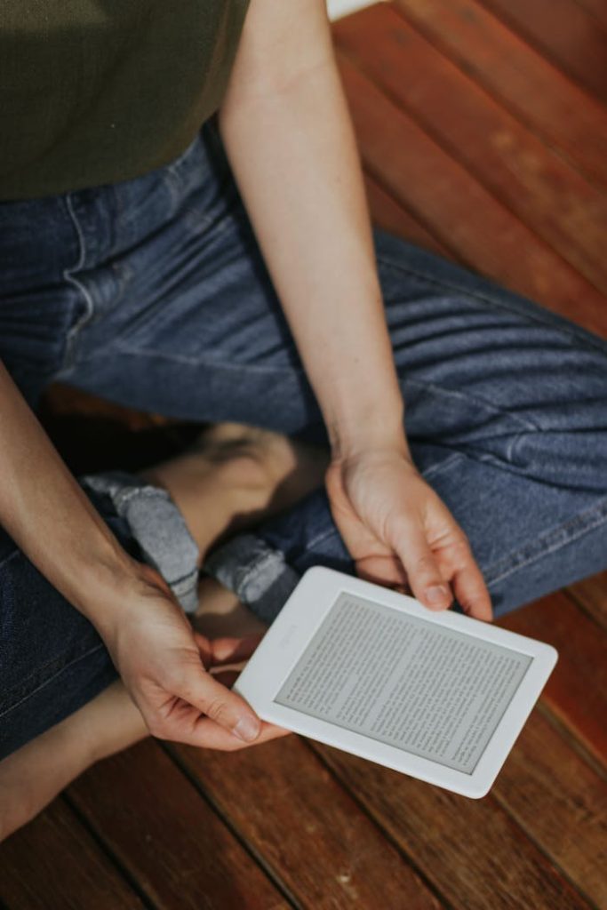A person reads a psychology ebook on a tablet while sitting on a wooden deck.